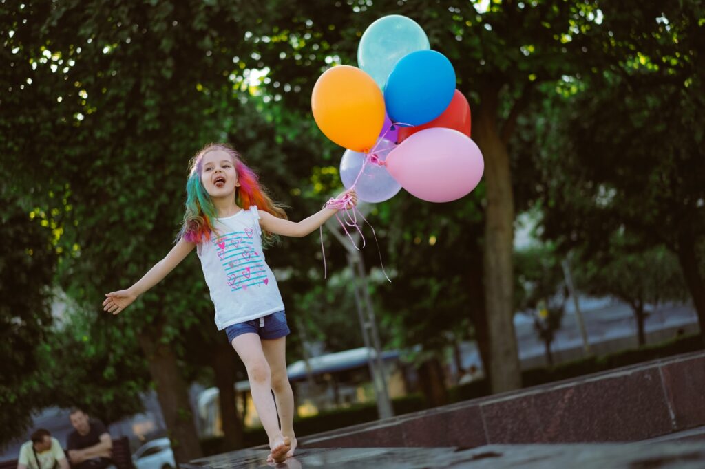 cute little girl holding colorful baloons